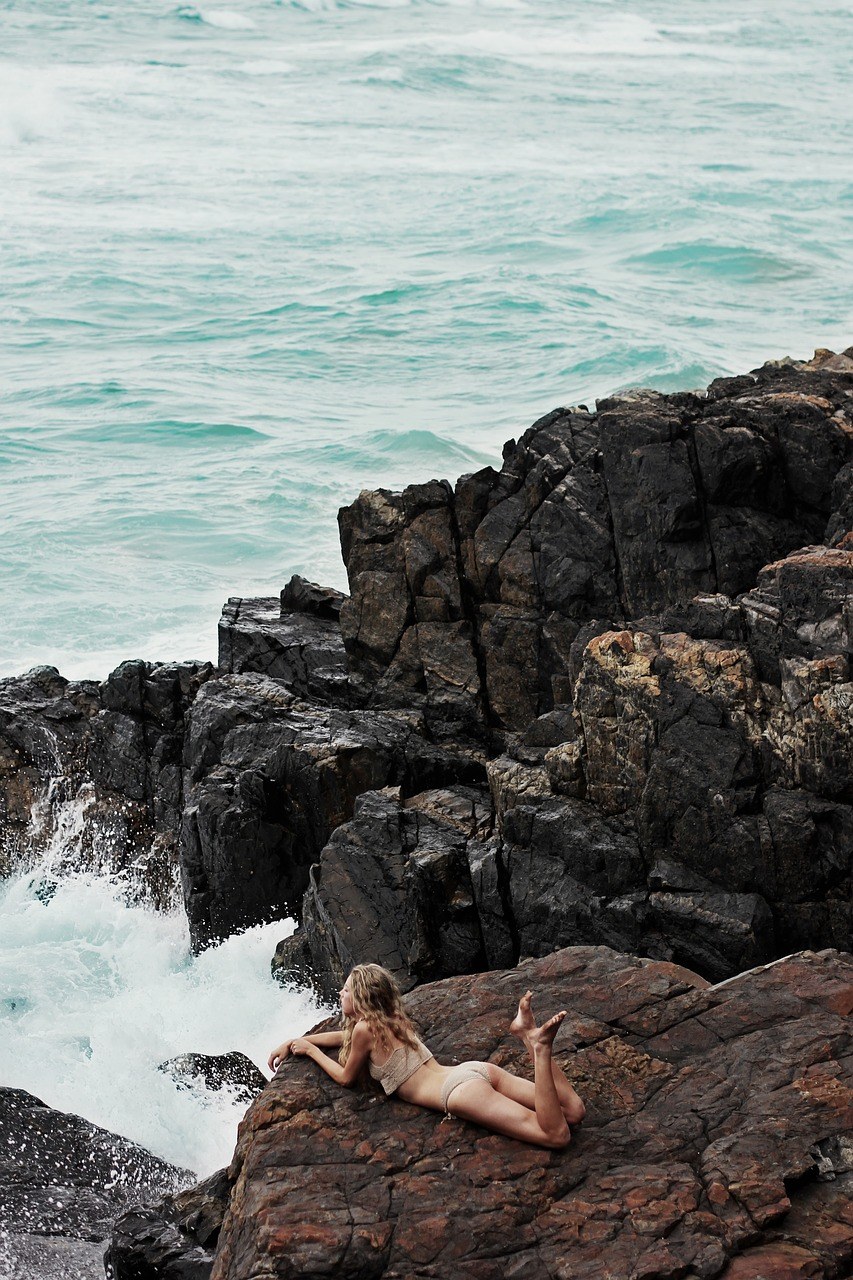 趴在海岸礁石上的泳装美女免费图片