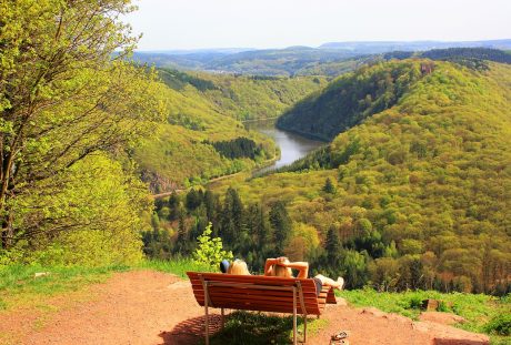 坐在户外长椅上观赏河流与绿色植被自然风景