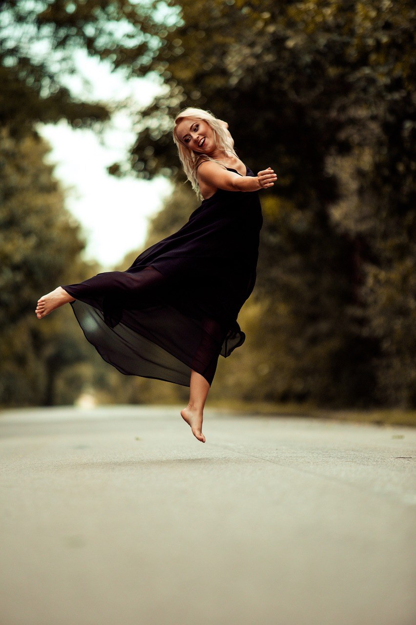 穿着黑色连衣裙跳跃起来的女人免费图片