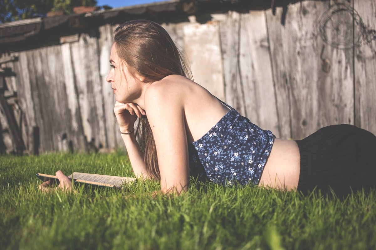 趴在草地上看书的美女阅读人物免费图片