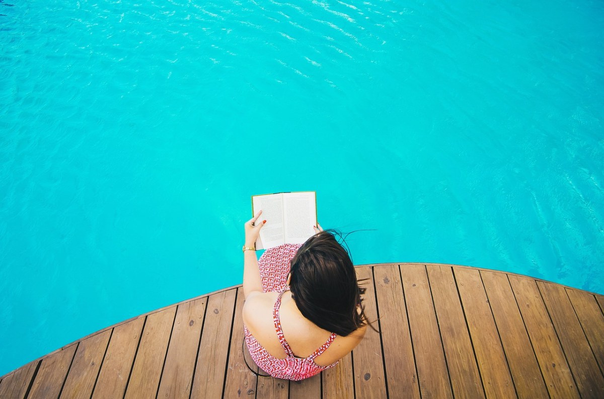 坐在游泳池边看书的女性人物免费图片