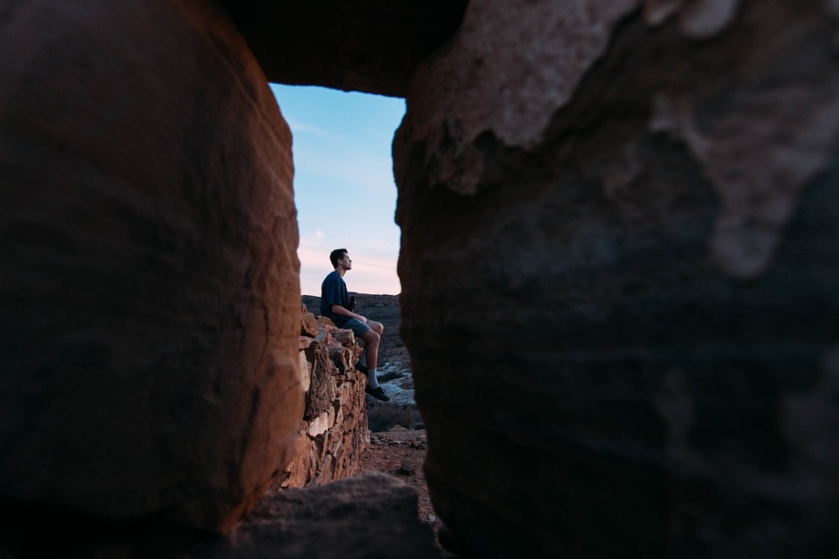 坐在岩石上遥望远方的男子免费图片