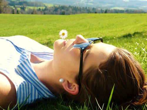 戴着眼镜躺在草地上休闲的女人