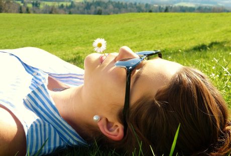 戴着眼镜躺在草地上休闲的女人