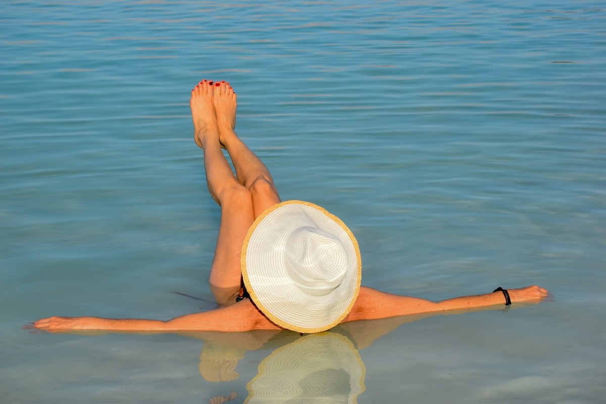 戴着草帽躺在水面上的女人免费图片
