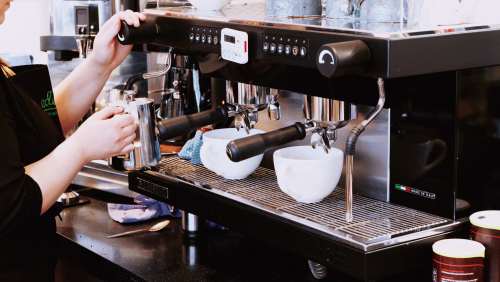 手拿咖啡壶在咖啡机到咖啡的图片