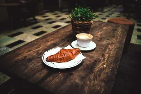 桌面上的一杯咖啡与牛角面包早餐图片