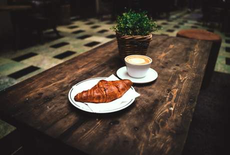 桌面上的一杯咖啡与牛角面包早餐图片